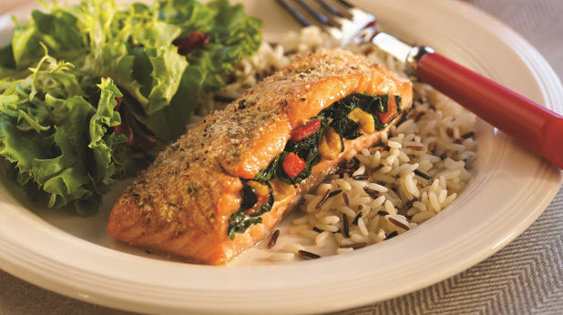 Salmon fillet stuffed with veggies on a plate with a salad and rice